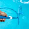 Limpeza manual de piscina com escova submersa.