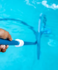 Limpeza manual de piscina com escova submersa.