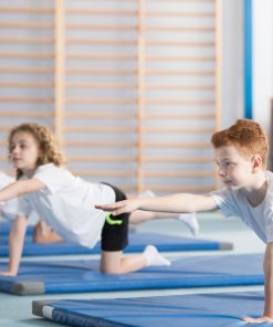 Crianças a praticar exercícios de equilíbrio e coordenação em tapetes de ginástica, promovendo o desenvolvimento motor e hábitos saudáveis através da actividade física.