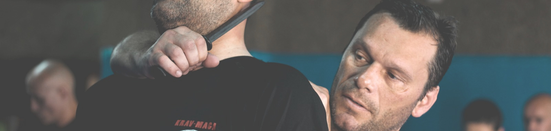 Treinador de Krav Maga ensina técnica de defesa contra ameaça com faca.