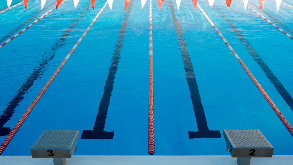 Piscina olímpica com pistas de natação delimitadas e blocos de partida, pronta para treinos ou competições de natação profissional.