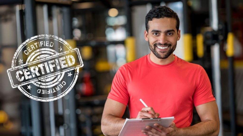Treinador de desporto certificado a sorrir numa academia, com bloco de notas na mão, transmitindo profissionalismo, confiança e preparação técnica.
