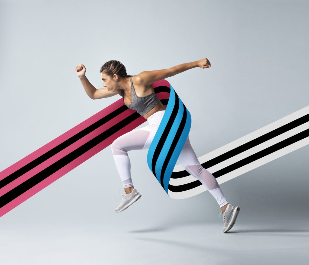 Mulher em posição de corrida, vestida com roupa desportiva, interagindo com faixas coloridas gráficas (rosa, azul e preto) que envolvem dinamicamente o seu corpo sobre fundo cinzento claro.